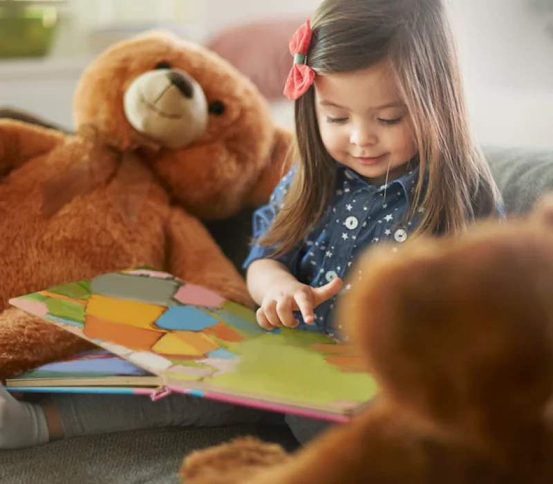 little-girl-reading-book-with-her-teddy-bears_329181-9347